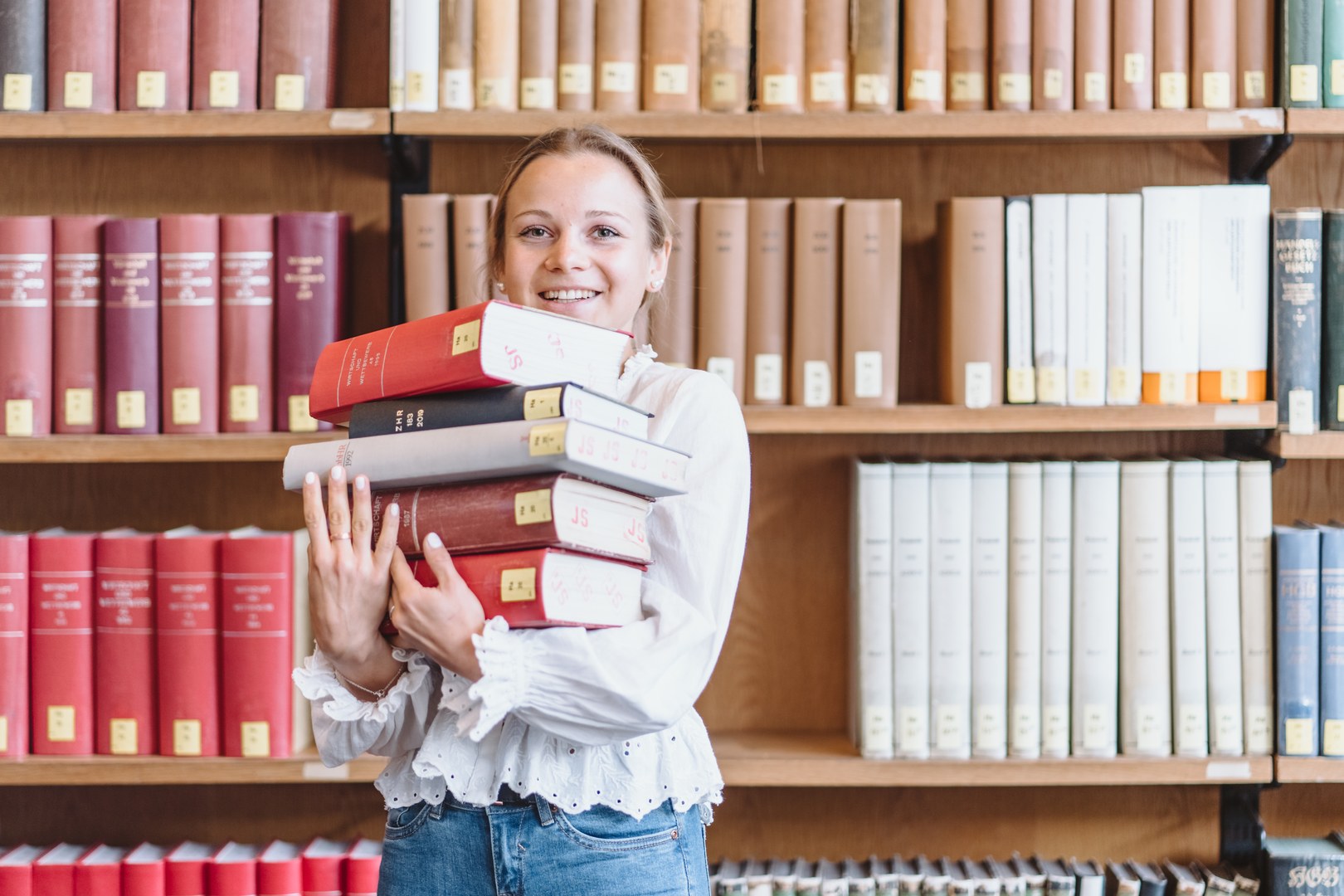 Eine Wissenschaftlerin und ein Wissenschaftler arbeiten hinter einer Glasfassade und mischen Chemikalien mit Großgeräten.