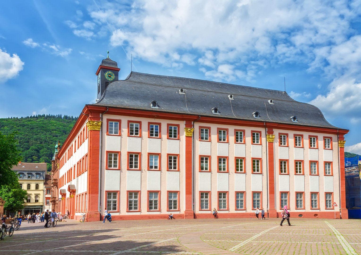 Eine Wissenschaftlerin und ein Wissenschaftler arbeiten hinter einer Glasfassade und mischen Chemikalien mit Großgeräten.