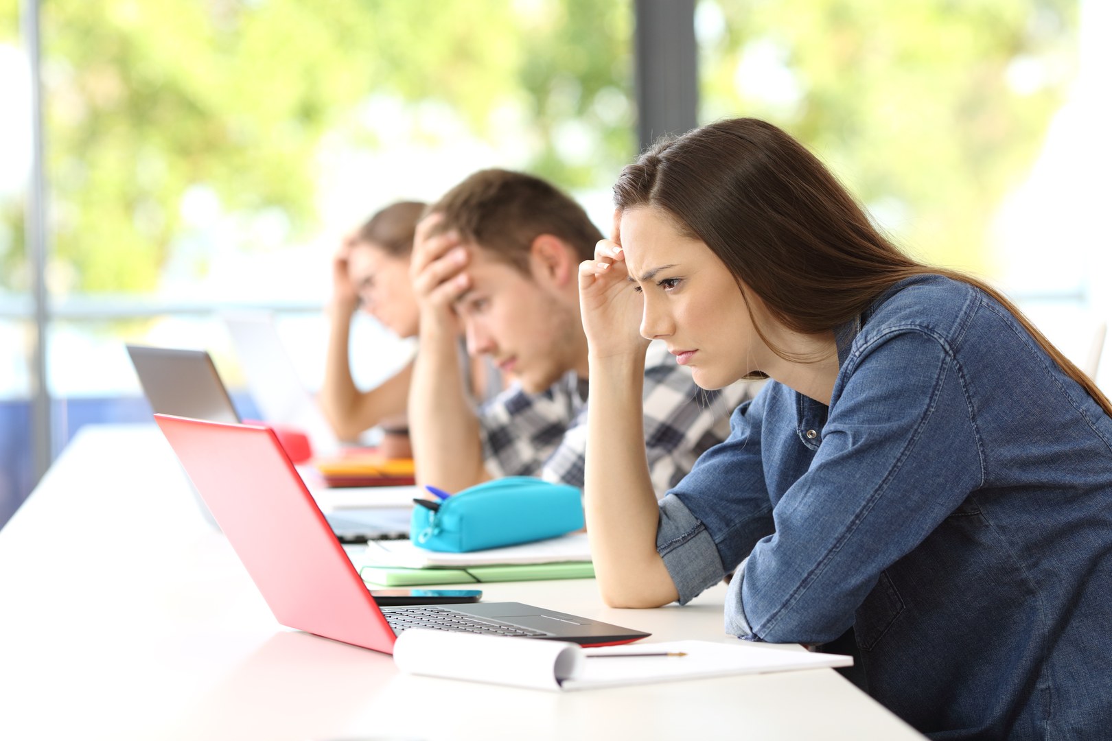 Eine Wissenschaftlerin und ein Wissenschaftler arbeiten hinter einer Glasfassade und mischen Chemikalien mit Großgeräten.