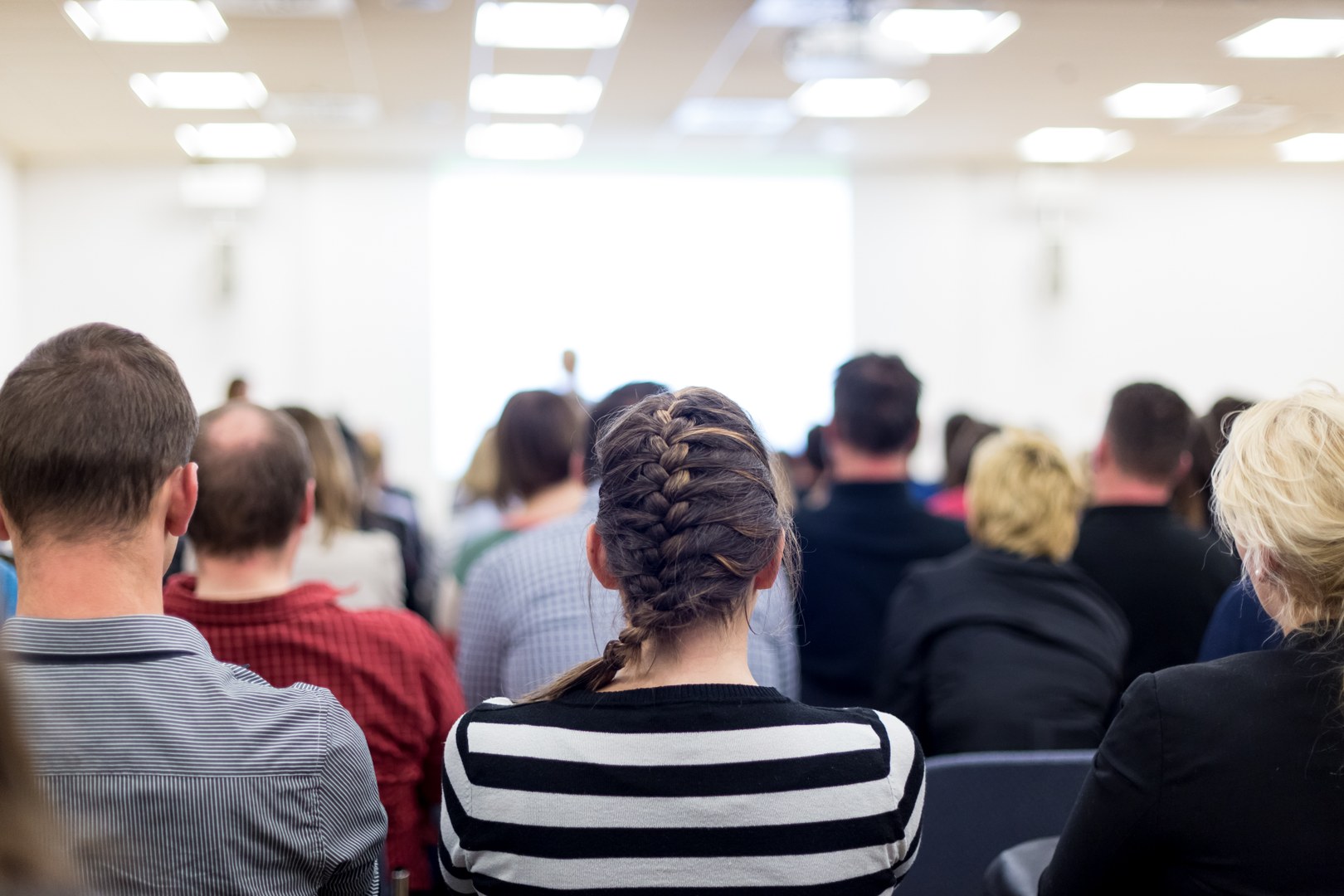 Eine Wissenschaftlerin und ein Wissenschaftler arbeiten hinter einer Glasfassade und mischen Chemikalien mit Großgeräten.