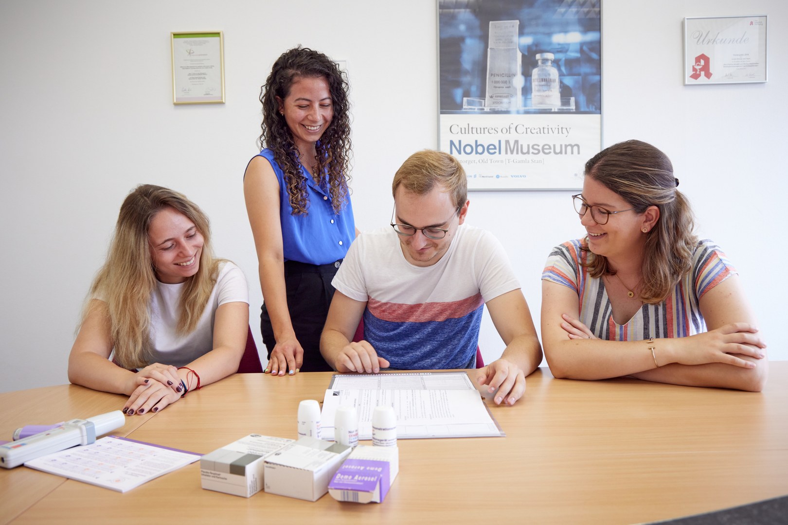 Eine Wissenschaftlerin und ein Wissenschaftler arbeiten hinter einer Glasfassade und mischen Chemikalien mit Großgeräten.