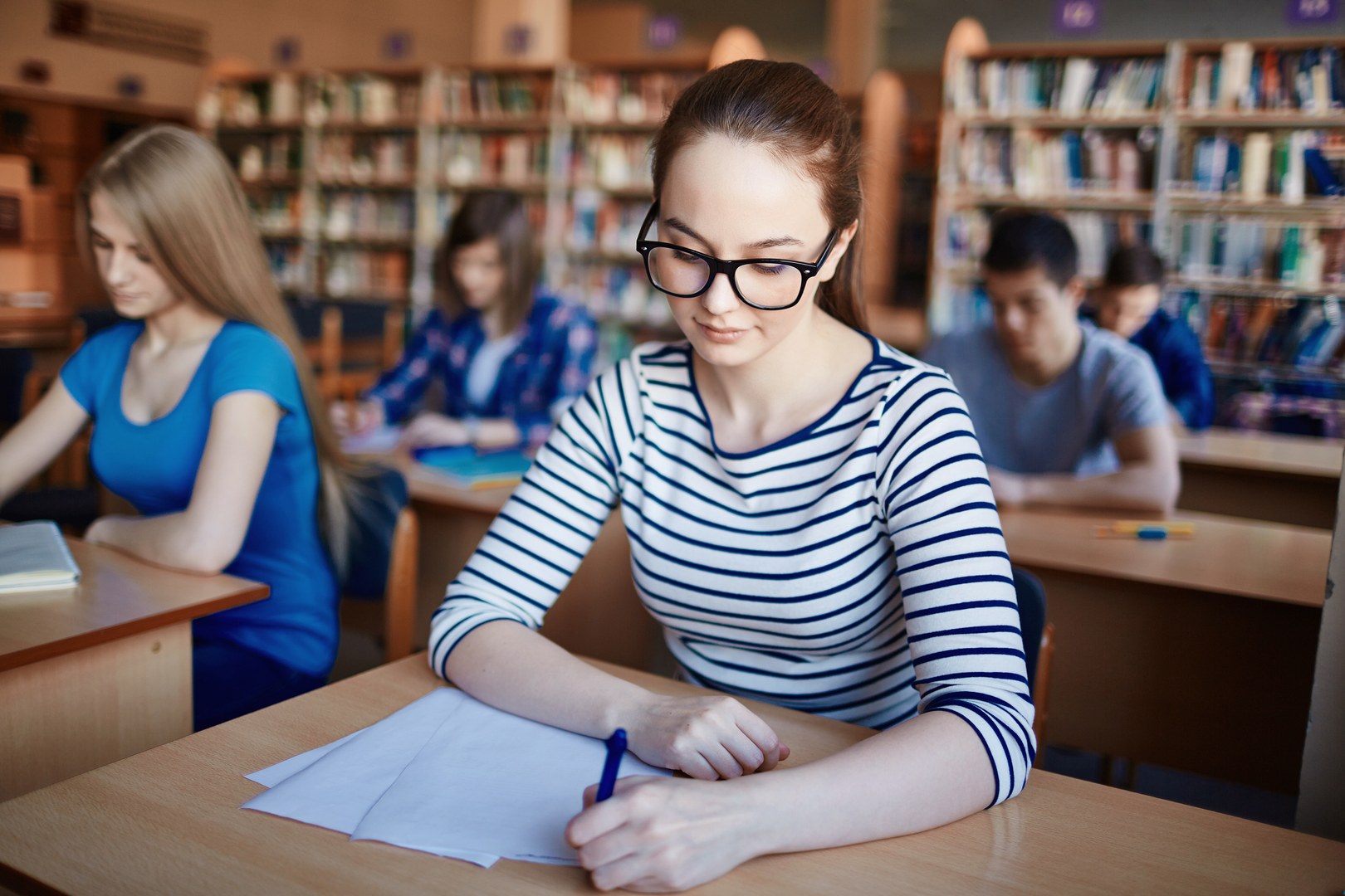 Eine Wissenschaftlerin und ein Wissenschaftler arbeiten hinter einer Glasfassade und mischen Chemikalien mit Großgeräten.